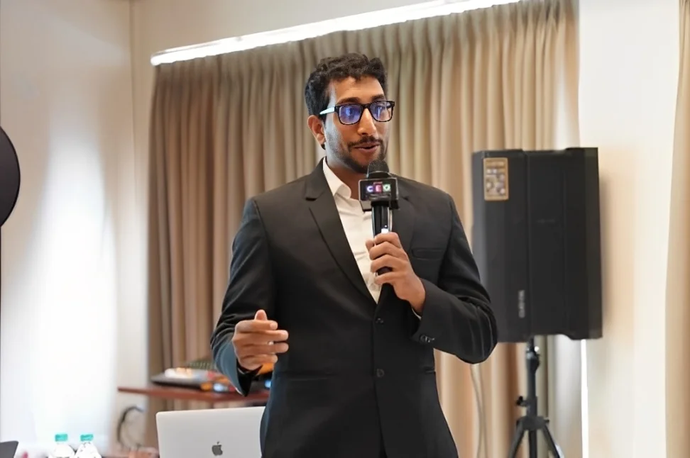 Nowfal Abdul Salam speaking with a microphone at a CEO business event in Kerala
